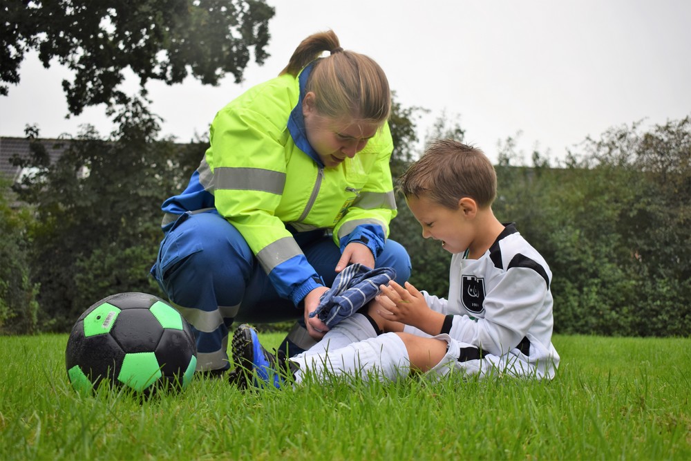 EHBO aan kinderen koelen van zere knie